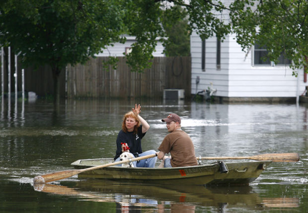Photo courtesy Matt Putney. Tammy Durnin, left, and her daughters dog Crystal are given a ride to safety by her neighbor Jamie Wood, right as the Cedar River flood water rises Thursday, June 12, 2008 in Waterloo, Iowa. Wood made numerous trips back and forth to evacuate his neighborhood with his boat. 